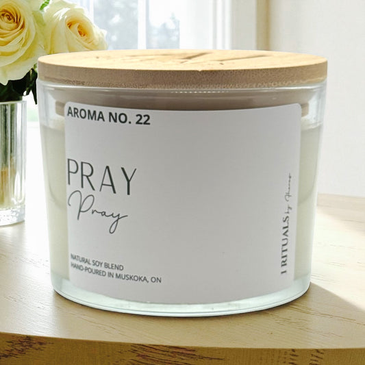 Candle with a wooden lid labeled 'Aroma No. 22 Pray' on a wooden surface.