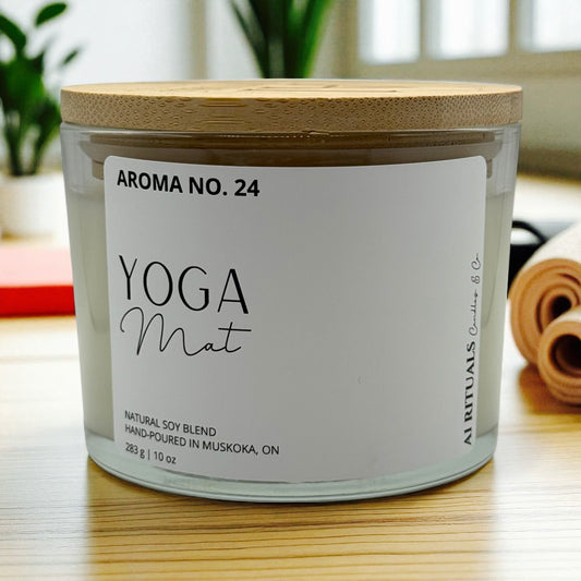 Candle labeled 'Yoga Mat' with a wooden lid on a surface.
